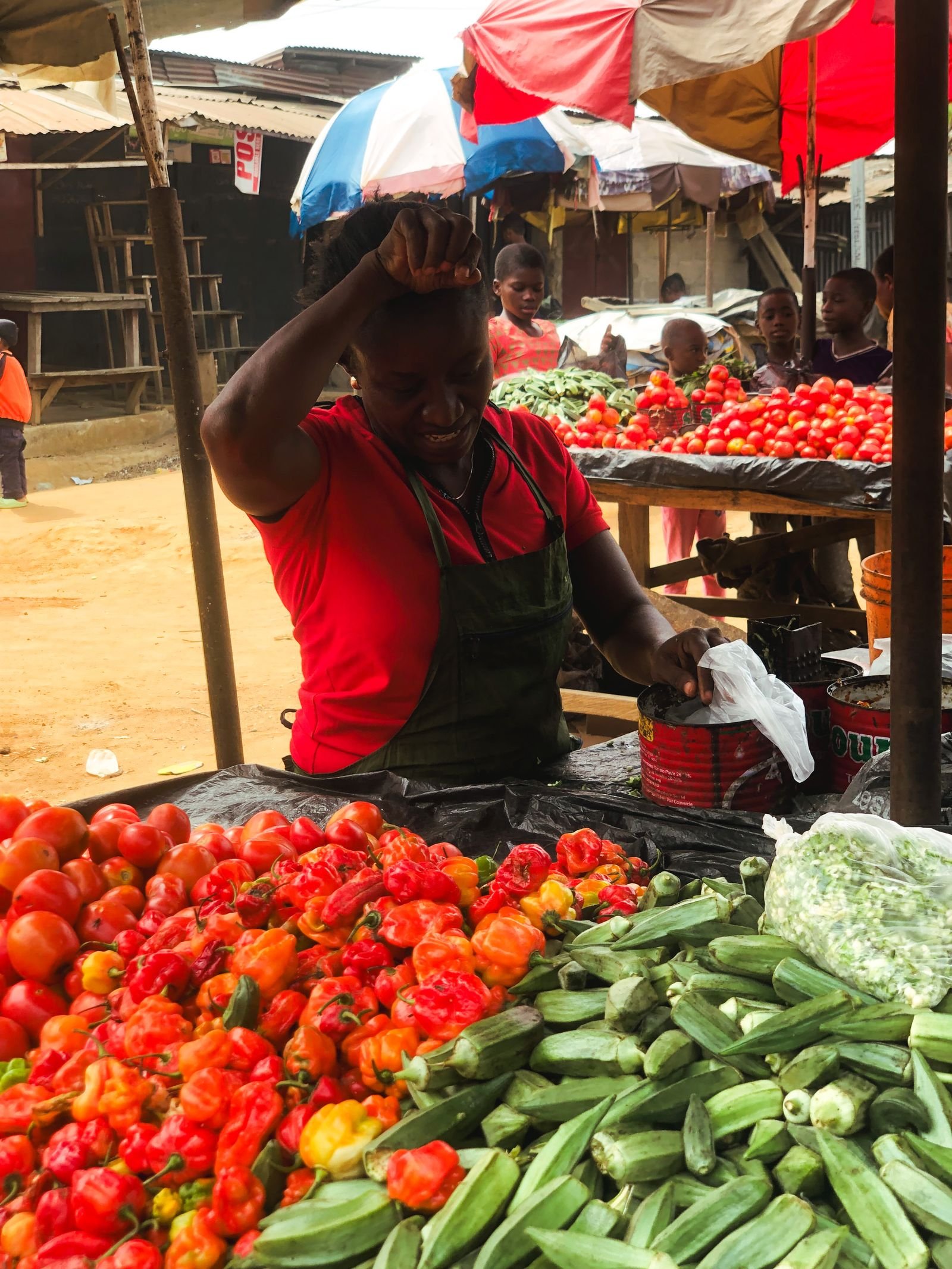 Commerçante vendant tomates, piments et légumes frais sur un marché