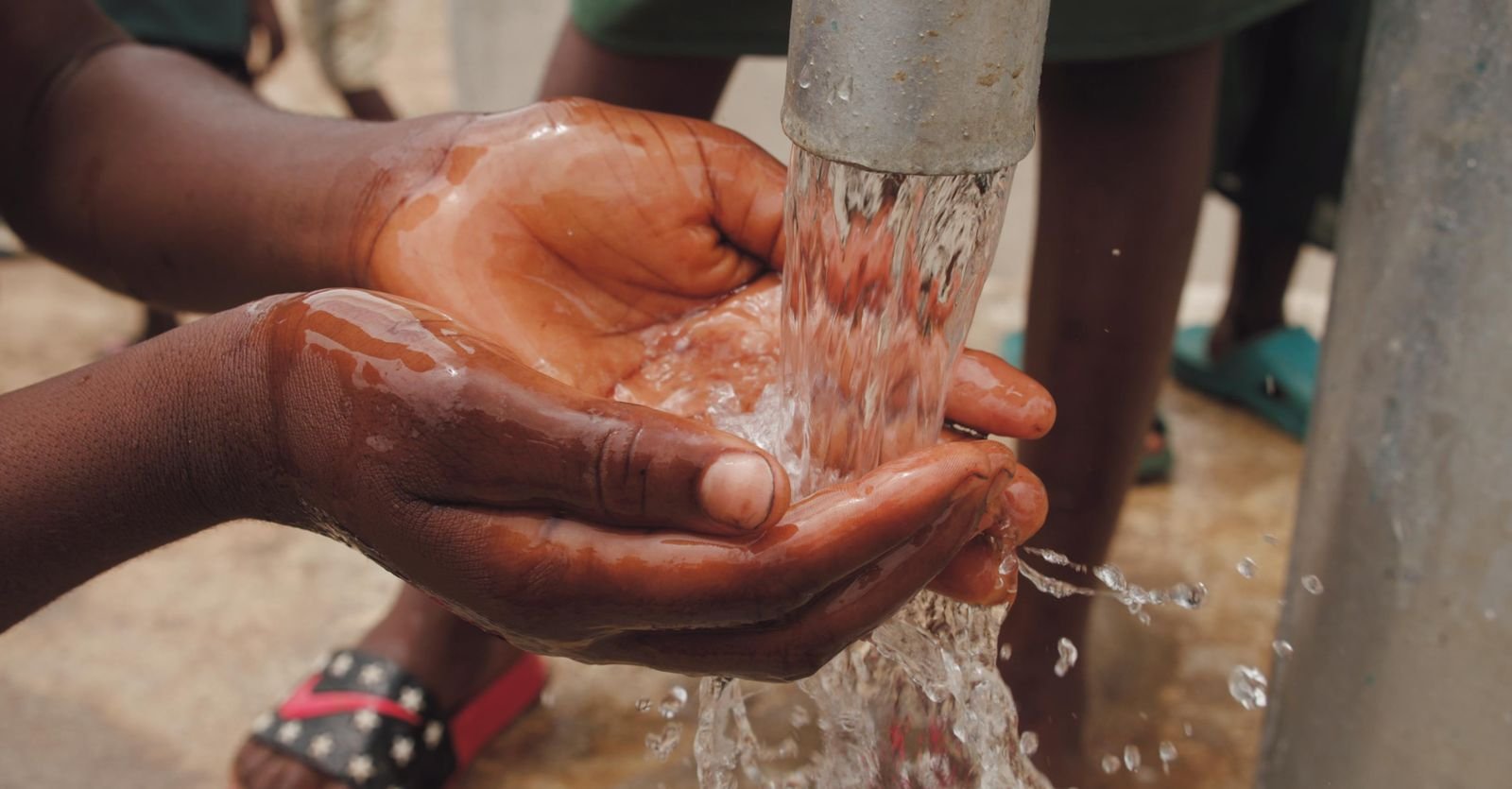 Mains d'enfant recueillant l'eau claire qui coule d'une pompe