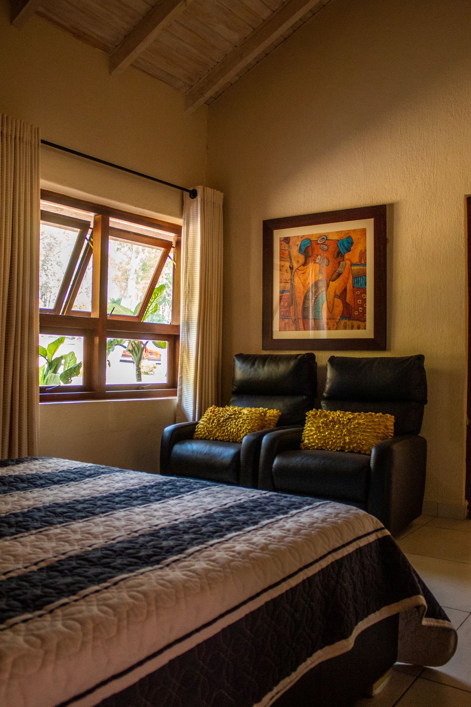 Chambre avec fauteuils, tableau coloré et fenêtre sur le jardin