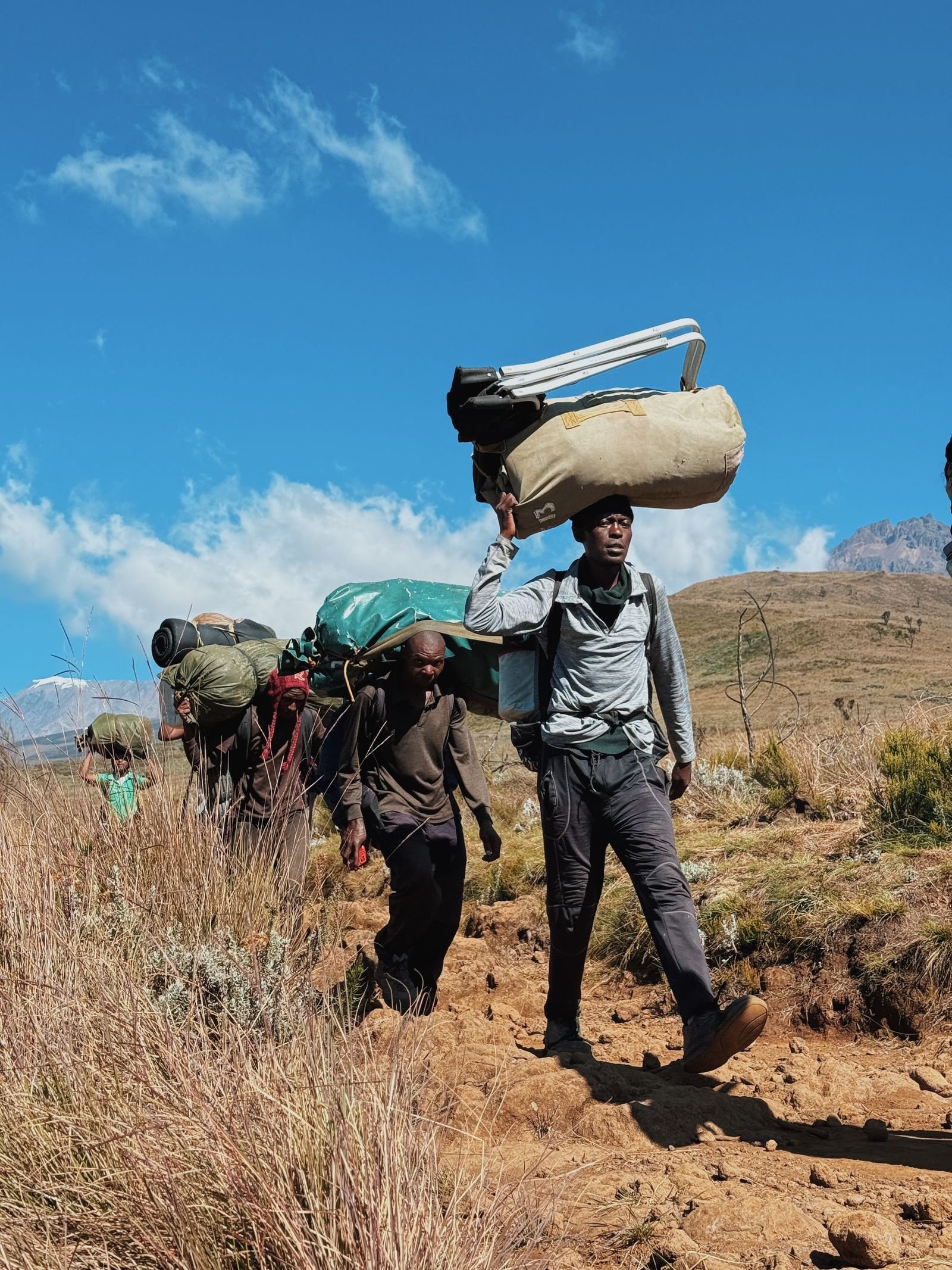 Porteurs chargés de matériel sur un sentier de montagne