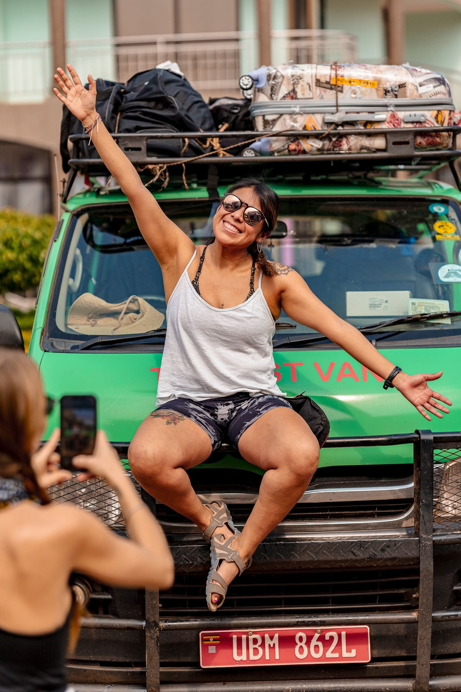 Voyageuse souriante assise sur le toit d'un véhicule de safari