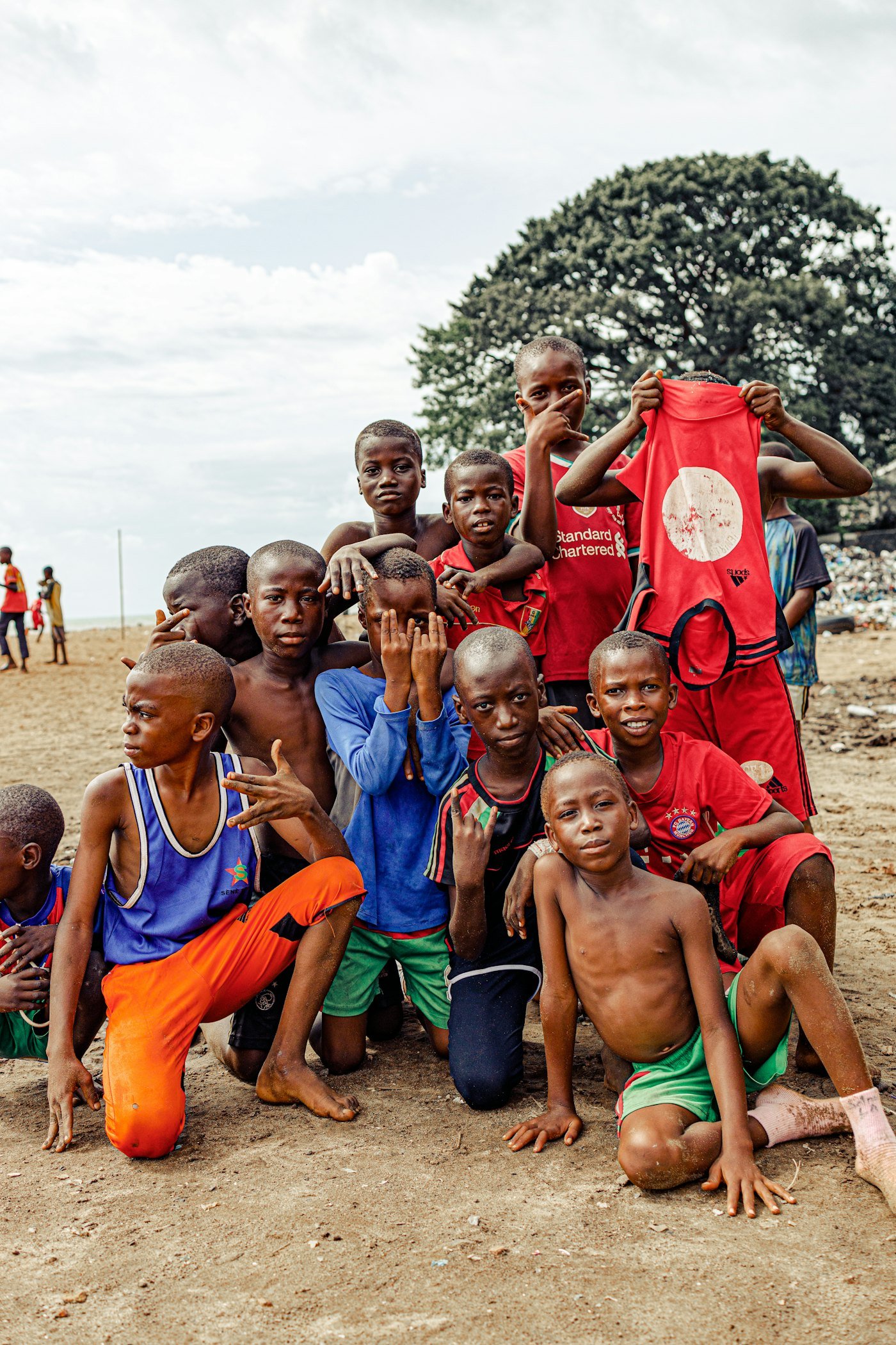 Groupe d'enfants et d'adolescents posant ensemble sur un terrain de football en terre