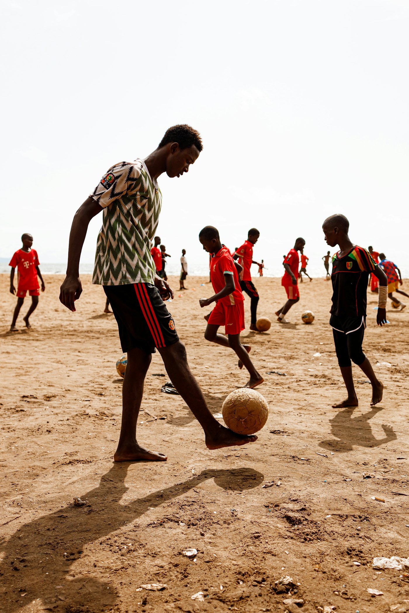 Jeunes joueurs disputant un match de football pieds nus sur le sable