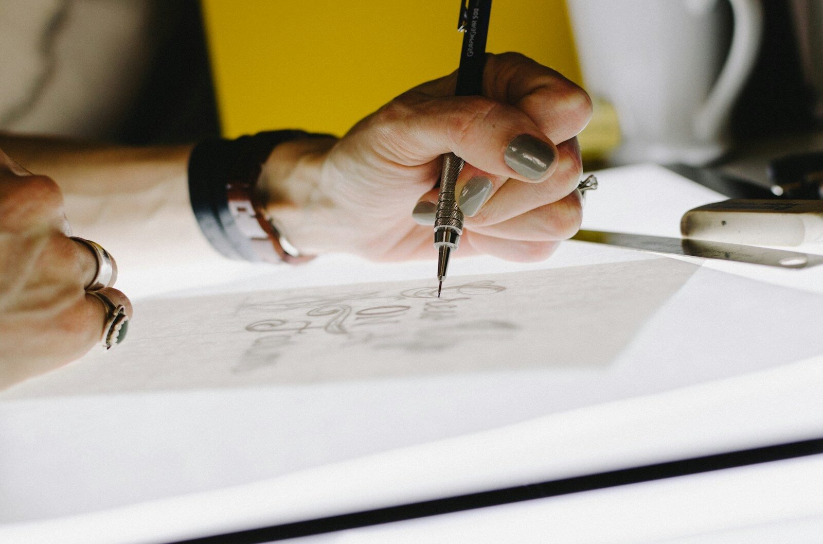 Hand sketching lettering on tracing paper with a mechanical pencil